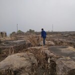 a man walking over large stones