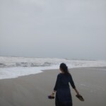 woman walking on a beach with shoes in hand and having fun