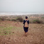 woman with a backpack on the sandy beach